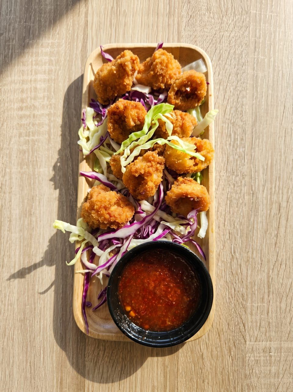 Crispy fried shrimp with shredded red and green cabbage, served with a spicy dipping sauce.
